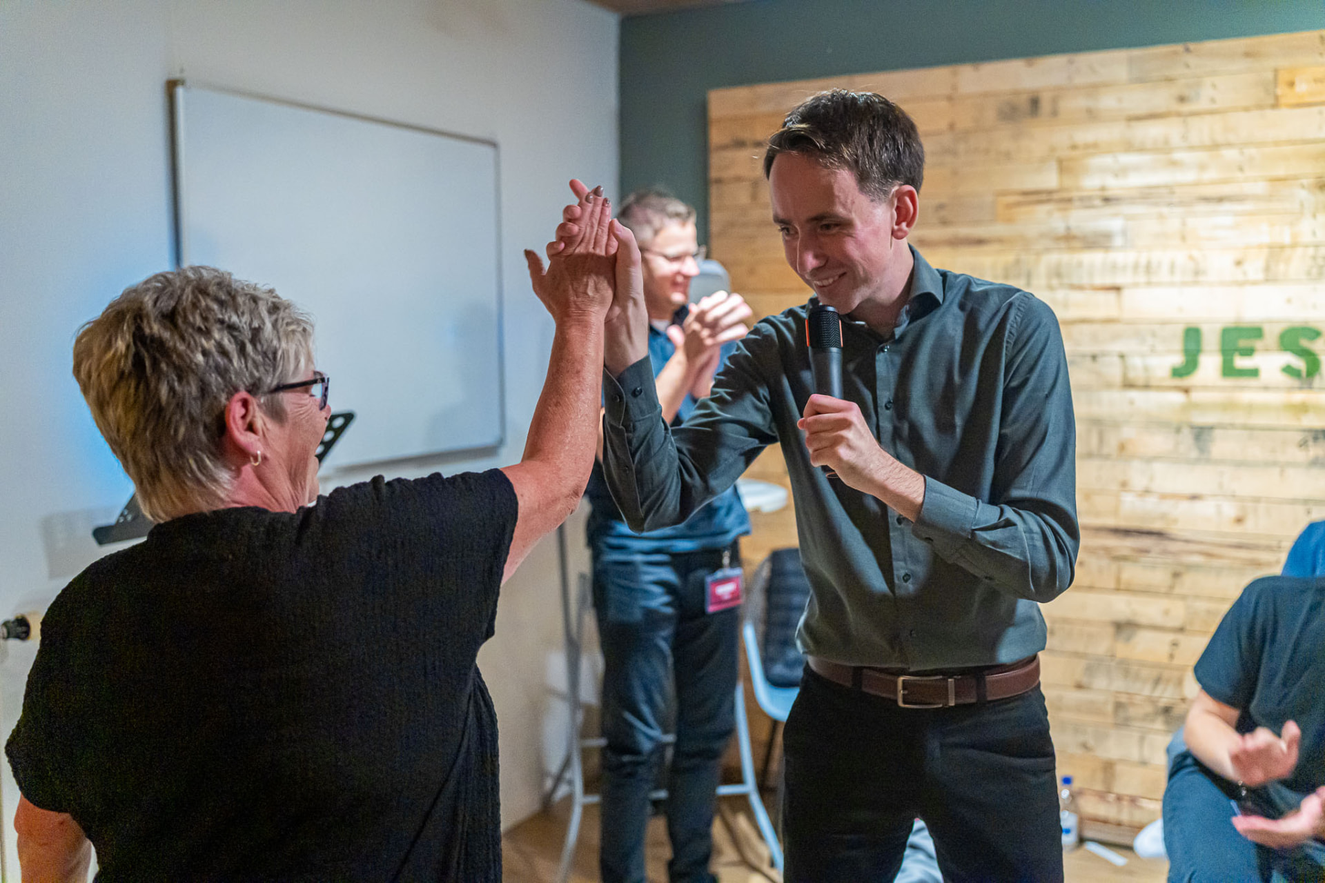 Vreugde na een getuigenis: een high-five tussen twee mensen tijdens de dienst
